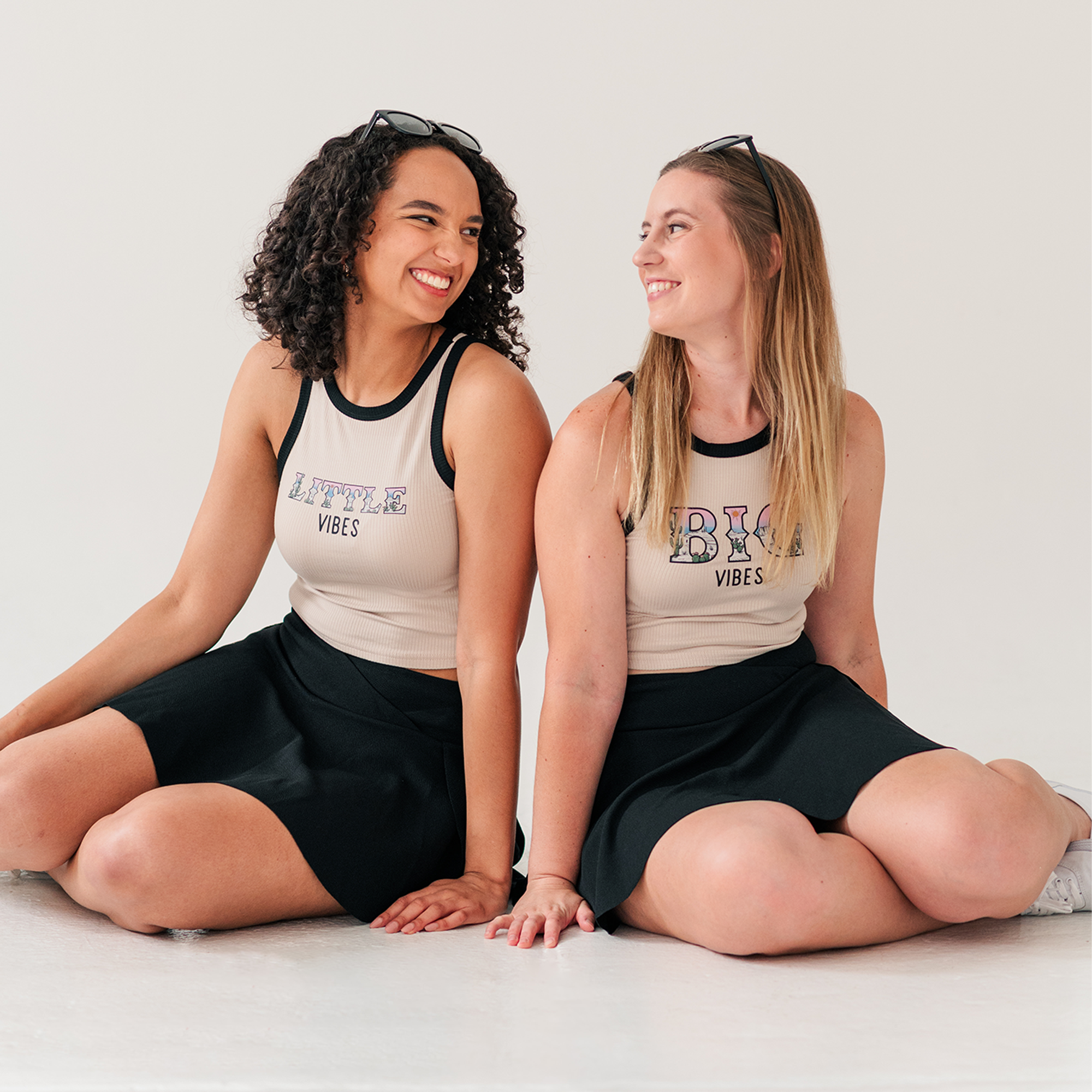 two women are sitting on the floor and smiling