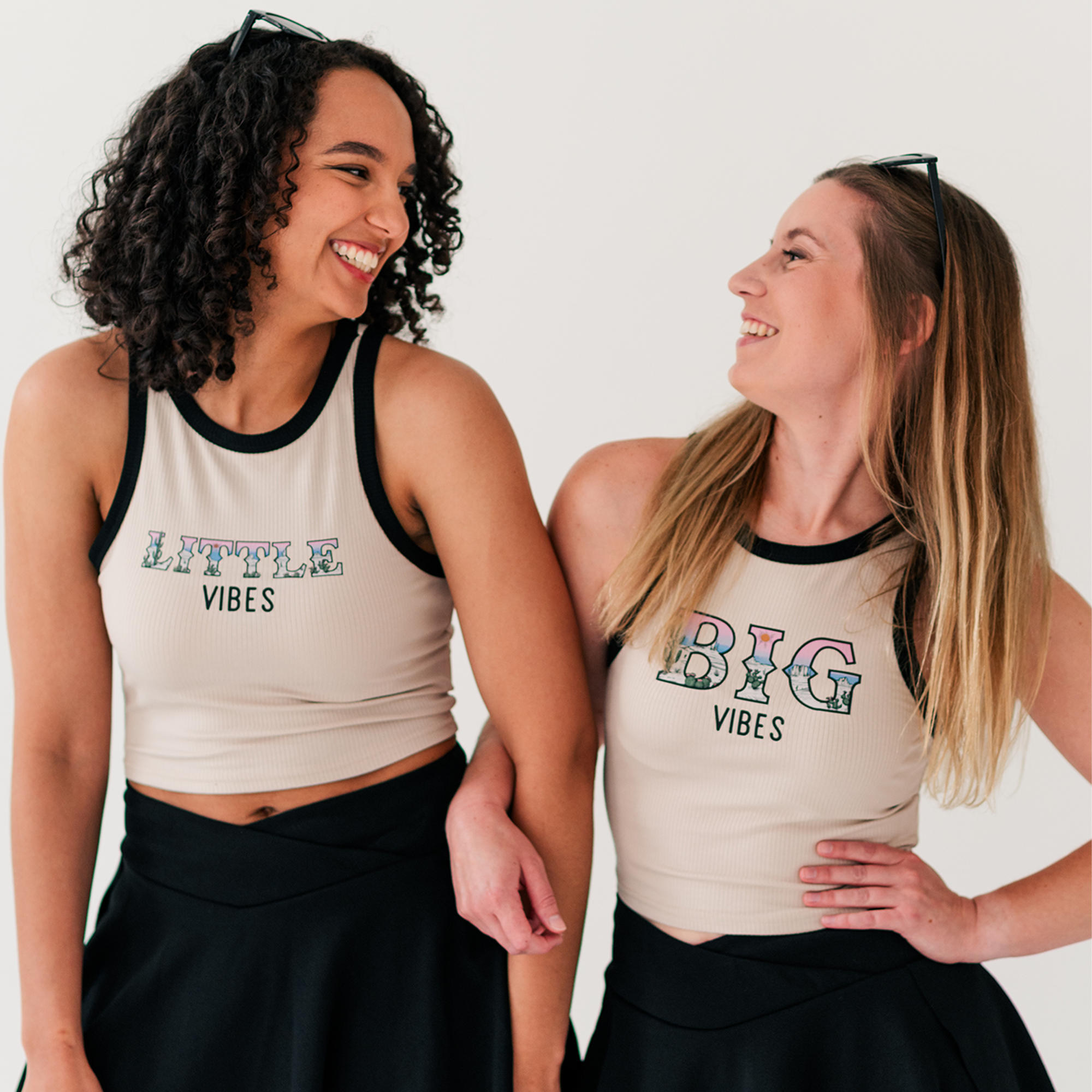 two women wearing matching shirts and black skirts