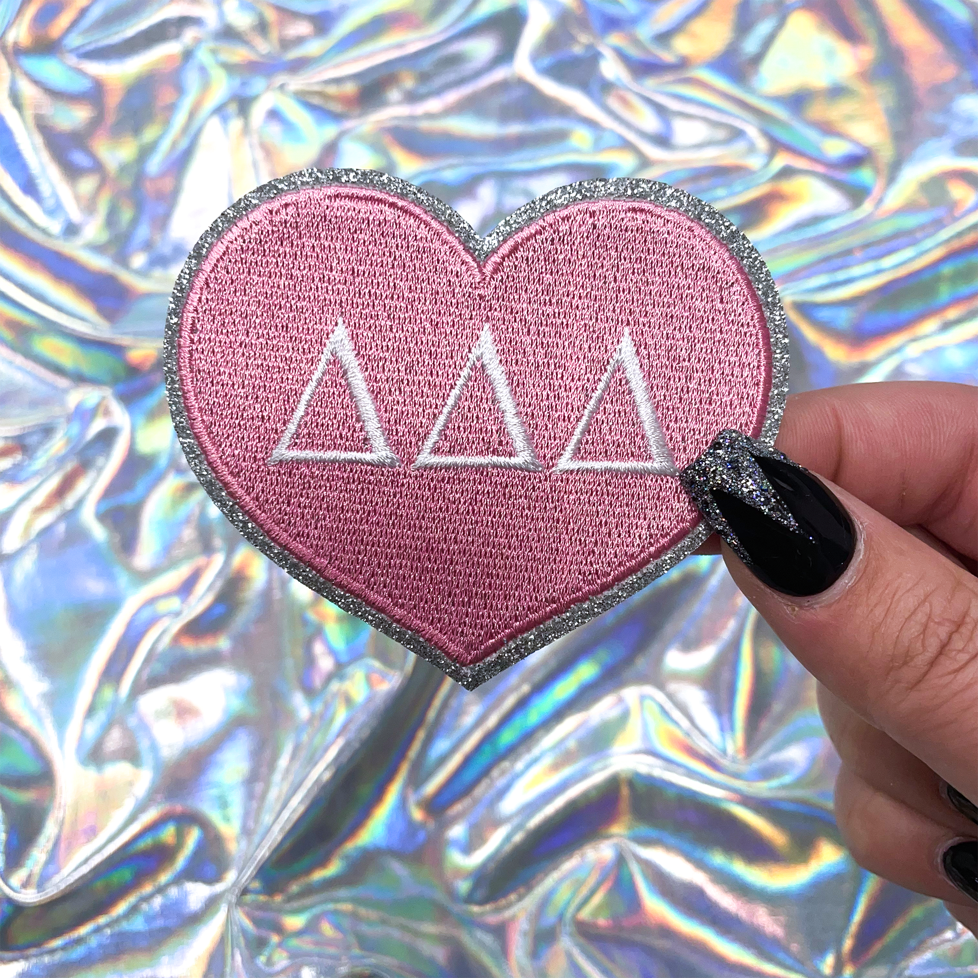 a hand holding a pink heart with the word delta on it