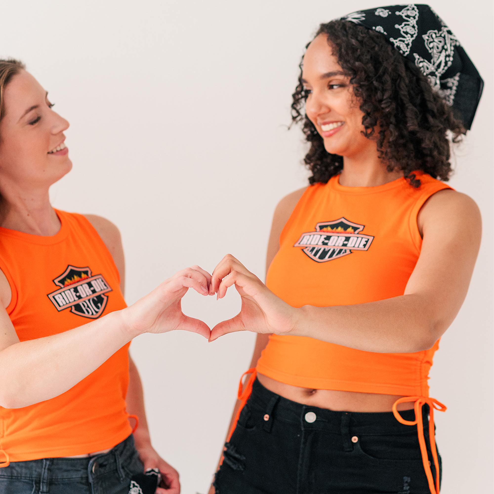 two young women making a heart shape with their hands