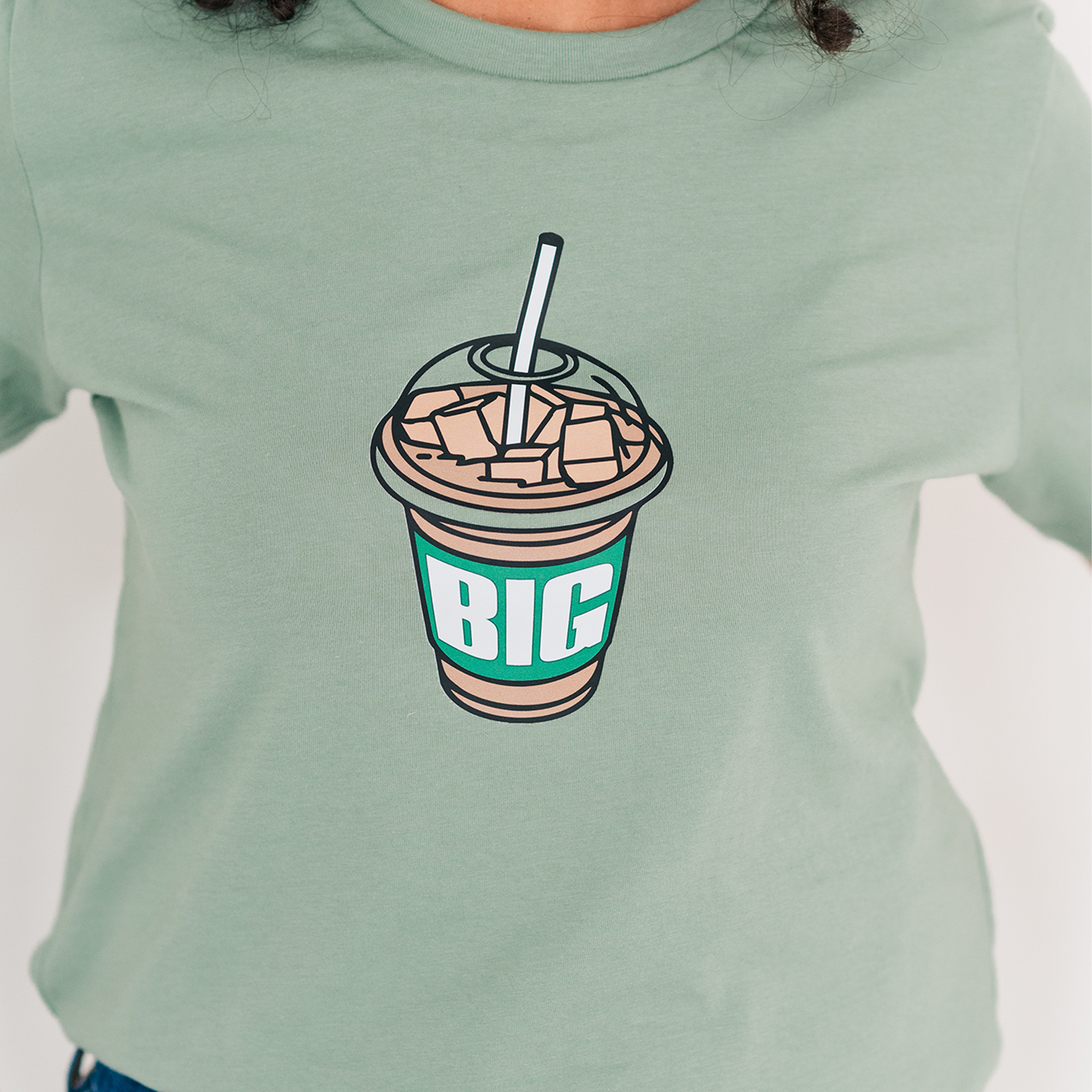 a woman wearing a green shirt with a big cup of coffee on it