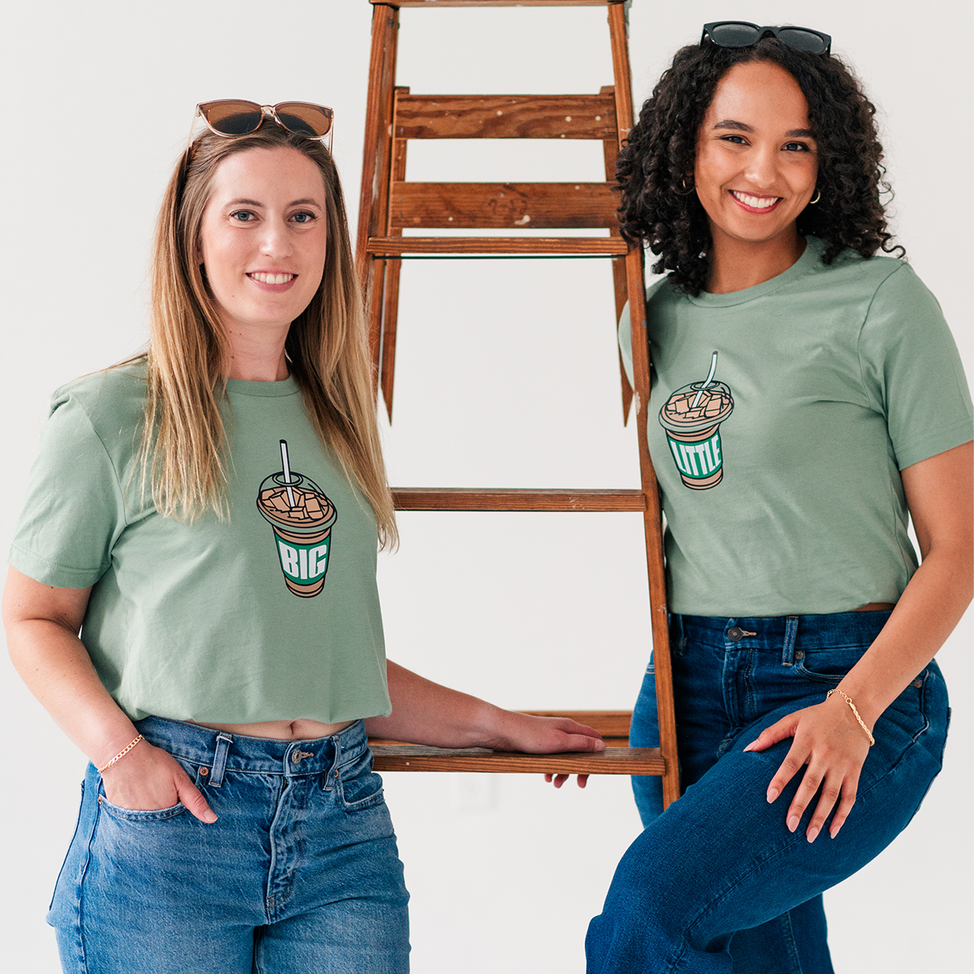 two women standing next to each other holding a ladder